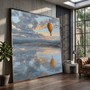 May include: Large framed landscape painting depicting a hot air balloon over water, reflecting the sky. The artwork uses a palette of blues, yellows, and oranges, suggesting a sunset. The painting is in a contemporary room.