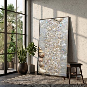Puede incluir: Una obra de arte enmarcada con un mosaico de fragmentos de conchas iridiscentes y conchas marinas. La obra es predominantemente blanca y beige, con un marco negro. La composición incluye una disposición vertical de trozos de concha y varias conchas intactas.