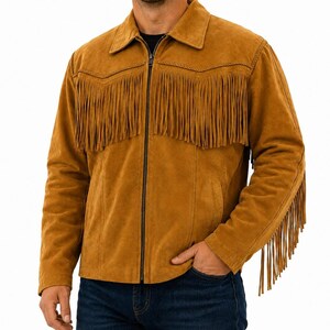 Puede incluir: Una chaqueta de ante color canela con cremallera frontal completa, cuello clásico y detalles de flecos largos en el pecho y a lo largo de las mangas. La chaqueta tiene un corte estructurado con costuras visibles y una textura suave.