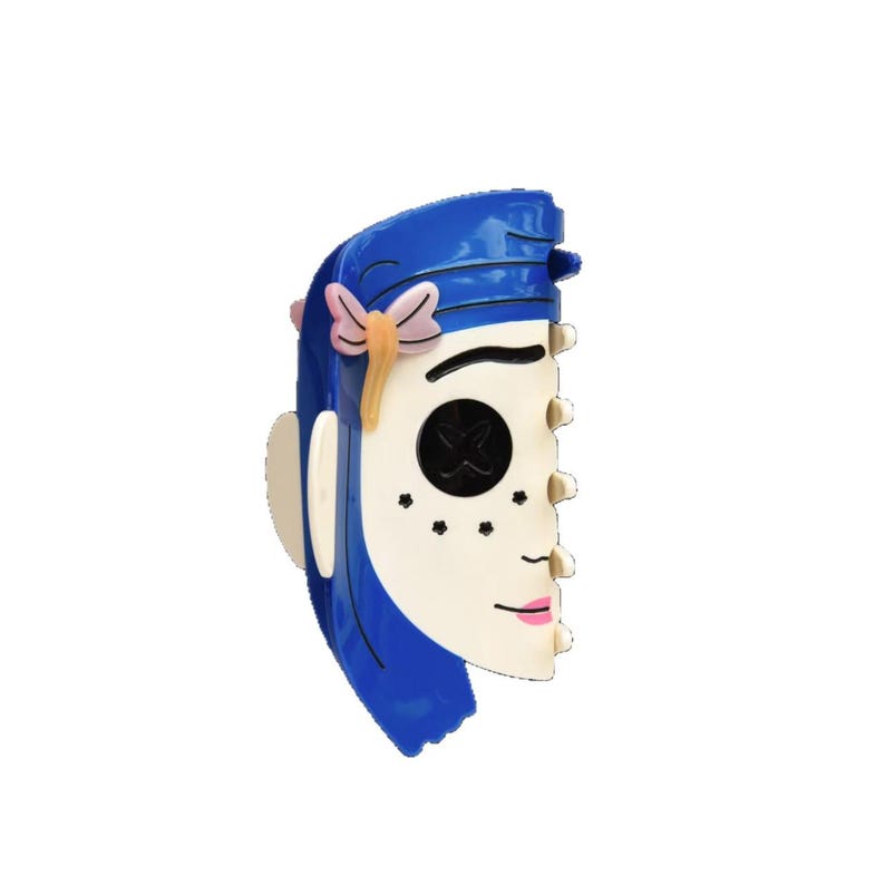 May include: A blue and white mask with a stylized face, featuring blue hair, a pink bow, and black button eyes. The mask has a side profile with a pink lip and freckles, perfect for cosplay or costume events.
