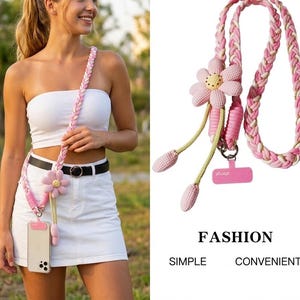 May include: Pink and white braided phone lanyard with a pink flower accent. The lanyard has a pink phone holder and a pink and yellow flower. The text "FASHION SIMPLE CONVENIENT" is at the bottom of the image.
