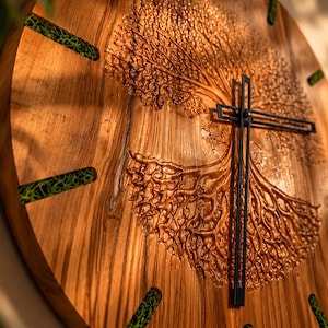 May include: A round wooden wall clock featuring a carved tree of life design on the face. The clock has black metal hands and hour markers filled with bright green preserved moss, set against the natural grain of the light brown wood surface.