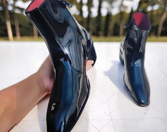 Handmade black patent leather ankle boots with a glossy finish and a side zipper.