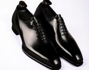 May include: A pair of black leather oxford shoes with a high-gloss finish, featuring a closed lacing system, thin black laces, and a pointed toe design. Each shoe includes a black plastic shoe tree inserted into the heel area for shape retention.