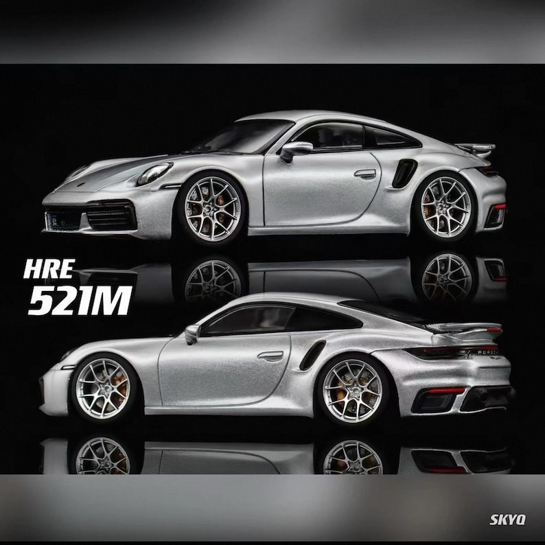 May include: Two silver sports cars are displayed, one above the other, against a black background. The cars have detailed wheels and aerodynamic designs. The text "HRE 521M" is visible on the left side of the image.