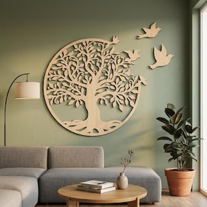 Op de afbeelding: Een cirkelvormig wandkunstwerk van lichtgekleurd hout met een gedetailleerde boom met complexe takken en bladeren. Drie afzonderlijke houten vogelsilhouetten zijn rechts van de boom geplaatst, alsof ze wegvliegen van de takken.