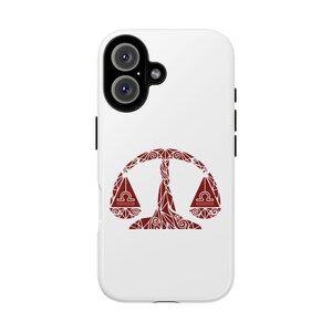 May include: White phone case featuring a red Libra zodiac symbol. The symbol is a stylized balance with intricate patterns. The phone case has a dual-lens camera and black side buttons.