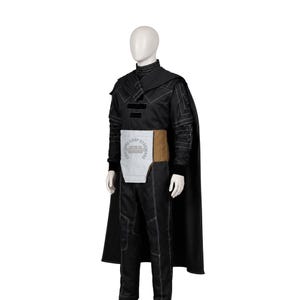 May include: A black long-sleeved costume featuring a high collar, a matching cape, and trousers with white contrast stitching. A light grey and tan rectangular waist panel is attached to the front, displaying the text COSTUME COSP STAR WARS.