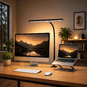 May include: A modern home office setup featuring a large computer monitor, a laptop on a stand, a wireless keyboard and mouse, and a black desk lamp. The monitor and laptop display a scenic landscape. The desk is made of wood.