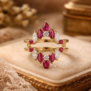 May include: A gold ring guard featuring a symmetrical arrangement of marquise-cut red rubies and marquise-cut white diamonds, accented with small round white diamonds. The open-frame design creates a crown-like shape with pointed gemstone settings.