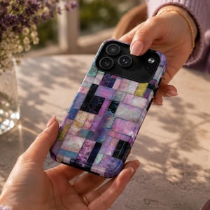 May include: A smartphone case featuring a mosaic pattern of rectangular tiles in shades of purple, pink, blue, and yellow with a shimmering, iridescent finish. The case has a black camera module cutout with three circular lens openings and a flash.
