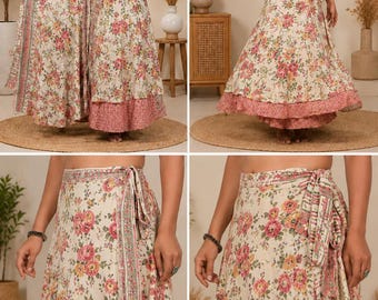 May include: A black sleeveless top paired with a cream-colored wrap skirt featuring a floral pattern in shades of pink, red, and green. The skirt has a side tie closure and a layered hem with a distinct pink patterned border at the bottom edge.