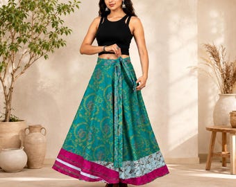 May include: A black sleeveless crop top paired with a floor-length teal wrap skirt featuring a repeating gold floral pattern, a wide magenta hem, and a light blue patterned border at the bottom. The skirt includes a matching fabric tie at the waist.