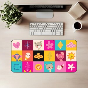 Könnte beinhalten: Eine farbenfrohe Schreibtischunterlage mit einem Raster aus Cartoon-Illustrationen. Das Design umfasst ein rosa Herz, einen Affen, einen Bären, eine Blume, eine Wolke, eine Sonne und andere geometrische Formen. Die Matte ist rechteckig.