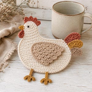 May include: A flat, crocheted chicken coaster in cream yarn with a tan wing, a rust-coloured comb and wattle, and a multi-coloured tail featuring rust, mustard, and brown segments. The chicken has a small black eye and two mustard-coloured feet.