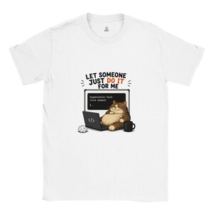 May include: A white short-sleeved t-shirt featuring a graphic of a brown tabby cat sitting at a laptop. The screen displays 'Segmentation fault (core dumped)'. Above the cat, the text reads 'LET SOMEONE JUST DO IT FOR ME' in black and orange.