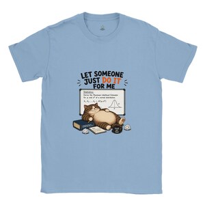 May include: A light blue t-shirt featuring a graphic of a brown tabby cat lying in front of a whiteboard with statistics equations. The text reads LET SOMEONE JUST DO IT FOR ME. The cat is next to a book labeled STATISTICS and a mug.