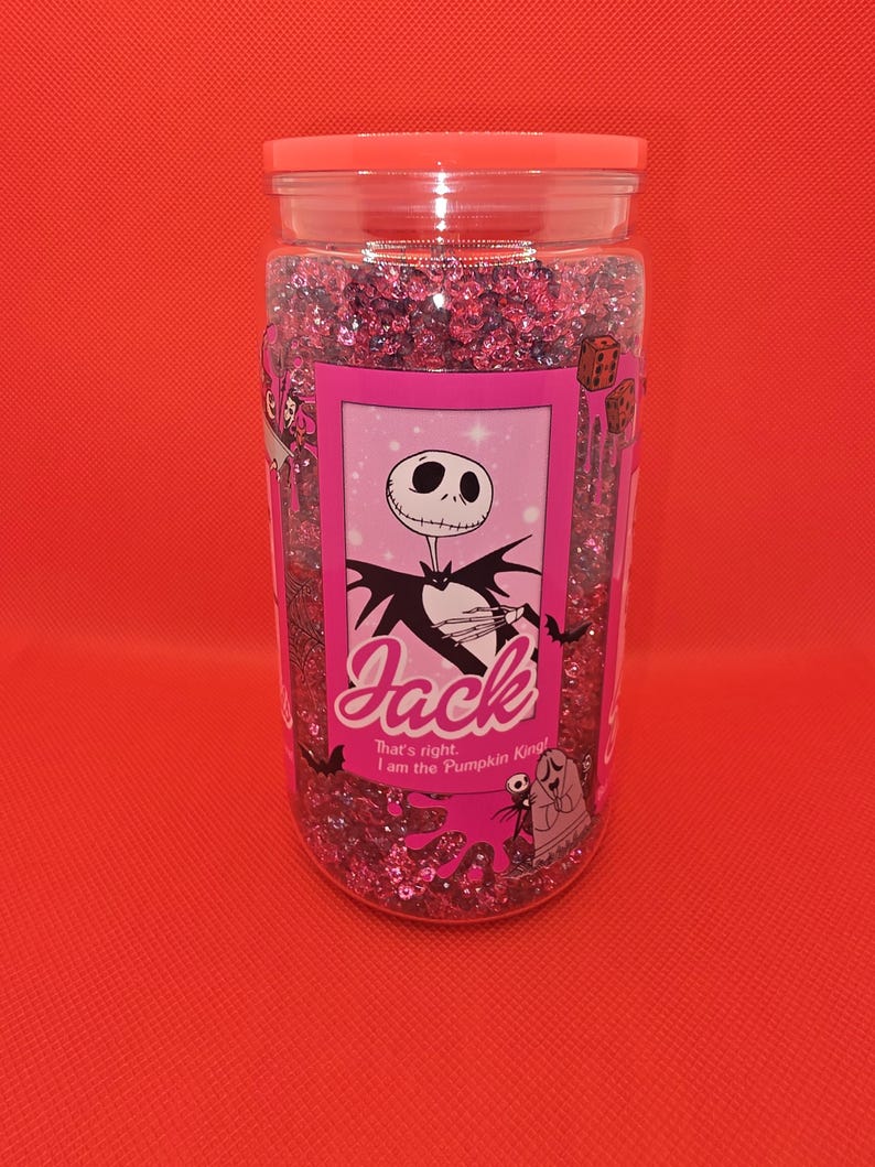 K&ouml;nnte beinhalten: Ein klares Glas mit rosa Glitzer und einem rosa Deckel. Das Glas hat ein rosa Etikett mit einer Illustration von Jack Skellington. Auf dem Etikett steht "Jack" und "That's right, I am the Pumpkin King!"