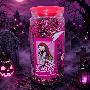 K&ouml;nnte beinhalten: Ein klares Glas mit einem rosa Deckel, gef&uuml;llt mit rosa Glitzer. Das Glas hat ein Etikett mit der Figur Sally aus The Nightmare Before Christmas. Der Hintergrund zeigt eine Friedhofsszene mit Vollmond.