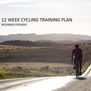 Pode incluir: Um ciclista em bicicleta de estrada numa estrada longa e reta. A imagem apresenta o texto "12 WEEK CYCLING TRAINING PLAN" e "BEGINNER FRIENDLY". A estrada estende-se à distância, com colinas e campos ao fundo.