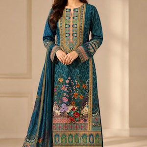 May include: A teal long-sleeved tunic dress featuring a vibrant floral print at the hem and a decorative patterned neckline. The garment includes a matching teal patterned shawl draped over one arm and solid teal trousers underneath.