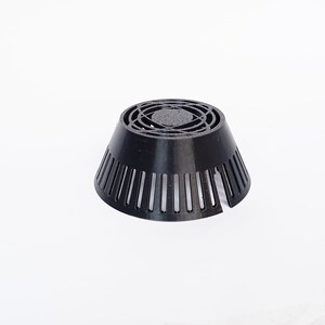 May include: A black plastic drain cover with a conical shape. The top features a circular, patterned design, while the sides have vertical slots. The object is designed to fit over a drain opening.