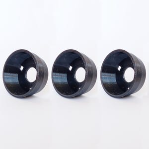 May include: Three black, cylindrical objects with a wide opening and a smaller, circular hole in the center. The objects have a textured surface and are arranged in a row against a white background. The design appears to be 3D printed.