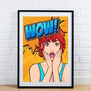 Puede incluir: Impresión enmarcada de arte pop que presenta a una mujer sorprendida con cabello rojo y la palabra "WOW!" en un bocadillo azul y blanco. El fondo es amarillo con un patrón de puntos y acentos negros. La mujer lleva una camiseta turquesa.