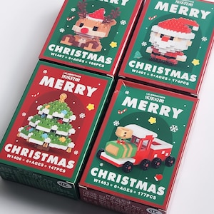 May include: Four Christmas-themed building block sets. Each box features a different design: a reindeer, Santa Claus, a Christmas tree, and a train. The boxes are red and green with the word "MERRY" and "CHRISTMAS" printed on them.