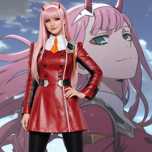 May include: A red cosplay outfit featuring a red jacket with black accents, black pants, and a white collar with an orange tie. The outfit is paired with a pink wig, white headband, and red horns. A large anime character is in the background.