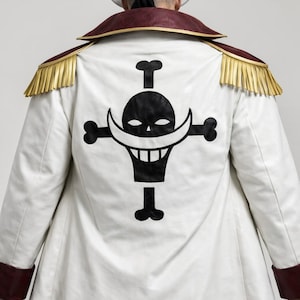 May include: White coat with a black skull and crossbones emblem on the back. The coat has a maroon collar and cuffs, with gold epaulettes. The emblem features a smiling skull with a distinctive mustache.