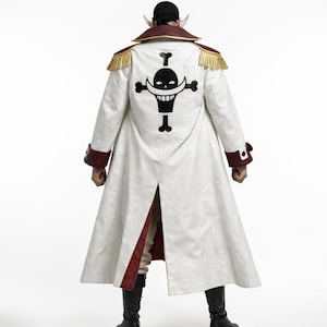 May include: A long white coat with a black skull and crossbones emblem on the back. The coat has red trim on the collar, cuffs, and inner lining. Gold fringe adorns the shoulders. Black boots complete the look.