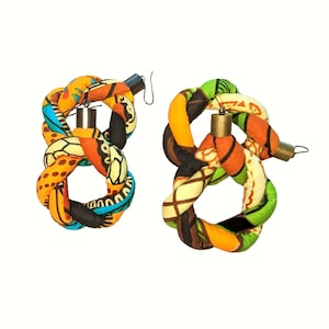 May include: A pair of colorful fabric earrings with a knotted design. The earrings are made of a bright orange, yellow, green, blue, and brown fabric. The earrings are attached to a metal hook.