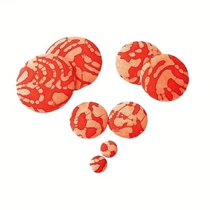 May include: A set of seven orange and white patterned round buttons. The buttons are various sizes and are arranged in a loose, asymmetrical pattern.