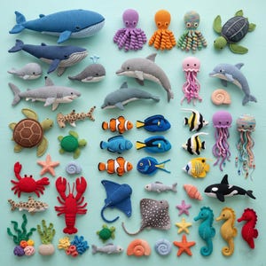 May include: A collection of handmade crochet sea creatures, including whales, dolphins, sharks, turtles, fish, and seahorses. The toys are in various colors, such as blue, gray, orange, and red. The arrangement is on a light blue surface.
