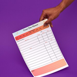 May include: A white Focus Time Planner with a colorful design is held against a purple background. The planner includes sections for Pomodoro Time Blocks, Main Tasks, and Notes. Text on the planner reads "Monitor your study sessions and improve your concentration over time."