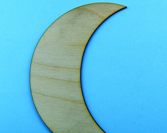 May include: A wooden crescent moon shape, cut out from a light brown piece of wood. The moon is on a light blue background.