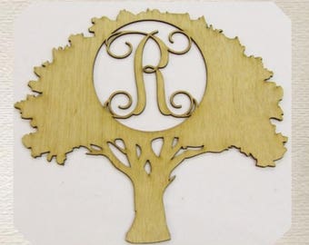 May include: A wooden cutout of a tree with a circle in the center, featuring the letter "R" in a decorative script font. The tree is a light brown color and has a detailed design.