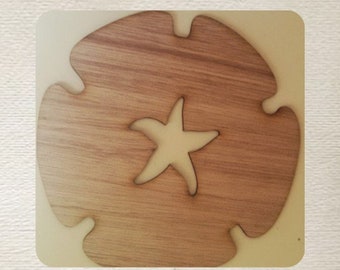 May include: A wooden cutout of a sand dollar with a starfish in the center. The sand dollar is light brown and the starfish is white.