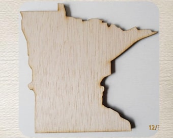 May include: A wooden cutout of the state of Minnesota. The cutout is light brown and has a smooth surface. The cutout is 12 inches tall.