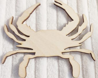 May include: A wooden cutout of a crab in a natural wood color. The crab is facing forward with its claws raised.