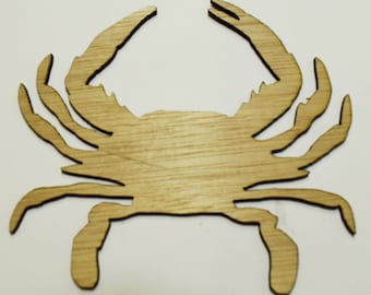 May include: A wooden cutout of a crab in a light brown color. The crab is facing forward with its claws raised.