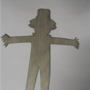 May include: A wooden cutout of a scarecrow with outstretched arms. The cutout is unpainted and has a rustic, natural wood finish.