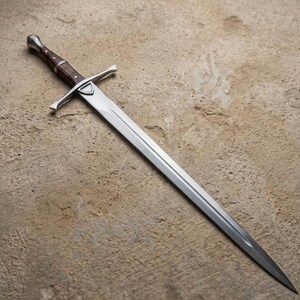May include: A long, silver sword with a polished blade and a brown wooden handle. The sword features a crossguard and a rounded pommel. The blade is approximately 36 inches long.