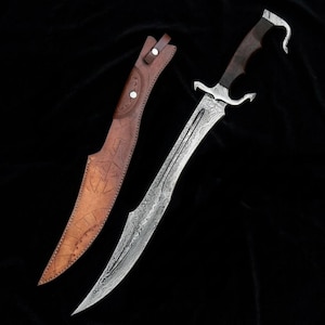 May include: A curved steel blade with a visible layered pattern and a dark wooden handle featuring a hooked pommel. Beside the blade is a tan leather sheath with stitched edges and embossed geometric line designs on the surface.