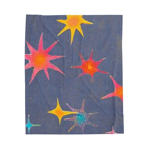 May include: A dark blue fabric featuring a scattered pattern of multi-pointed stars in vibrant shades of yellow, orange, pink, and teal. The stars vary in size and colour intensity, creating a celestial design across the entire surface of the textile.