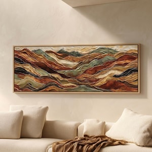 May include: A rectangular framed artwork depicting a layered mountain landscape. The artwork features a palette of warm earth tones, including shades of brown, orange, and green. The textured surface creates a sense of depth and dimension, evoking a natural, abstract aesthetic.
