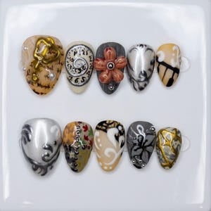 Ongles à coller gothiques vintage | Ambiance surréaliste et fantastique | Forme amande originale | Ongles argentés métallisés à motif filigrane | Ongles décorés de fleurs 3D complexes