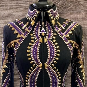 May include: Black equestrian show jacket with intricate gold and purple embellishments. The jacket features a high collar and a zipper closure. The design includes geometric patterns and decorative studs. The word "Signature" is written on the bottom right.