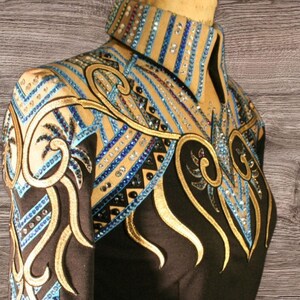 May include: Black equestrian show jacket with intricate gold and blue embroidery. The jacket features a high collar and is embellished with rhinestones. The word "Signature" is printed on the lower right side of the jacket.